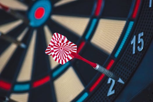 A dart striking the bullseye on a dartboard, showcasing precision and accuracy.